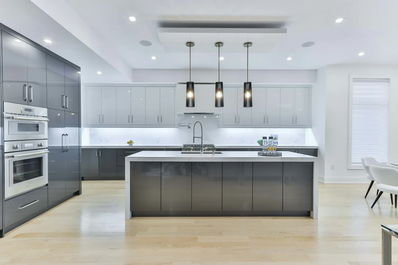 Stock illustration of kitchen fittings, a sink, island and pendant lighting in a grey kitchen.