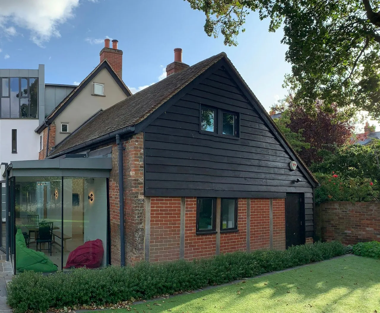 Stock architectural illustration of a glazed addition beside a brick house and garden.