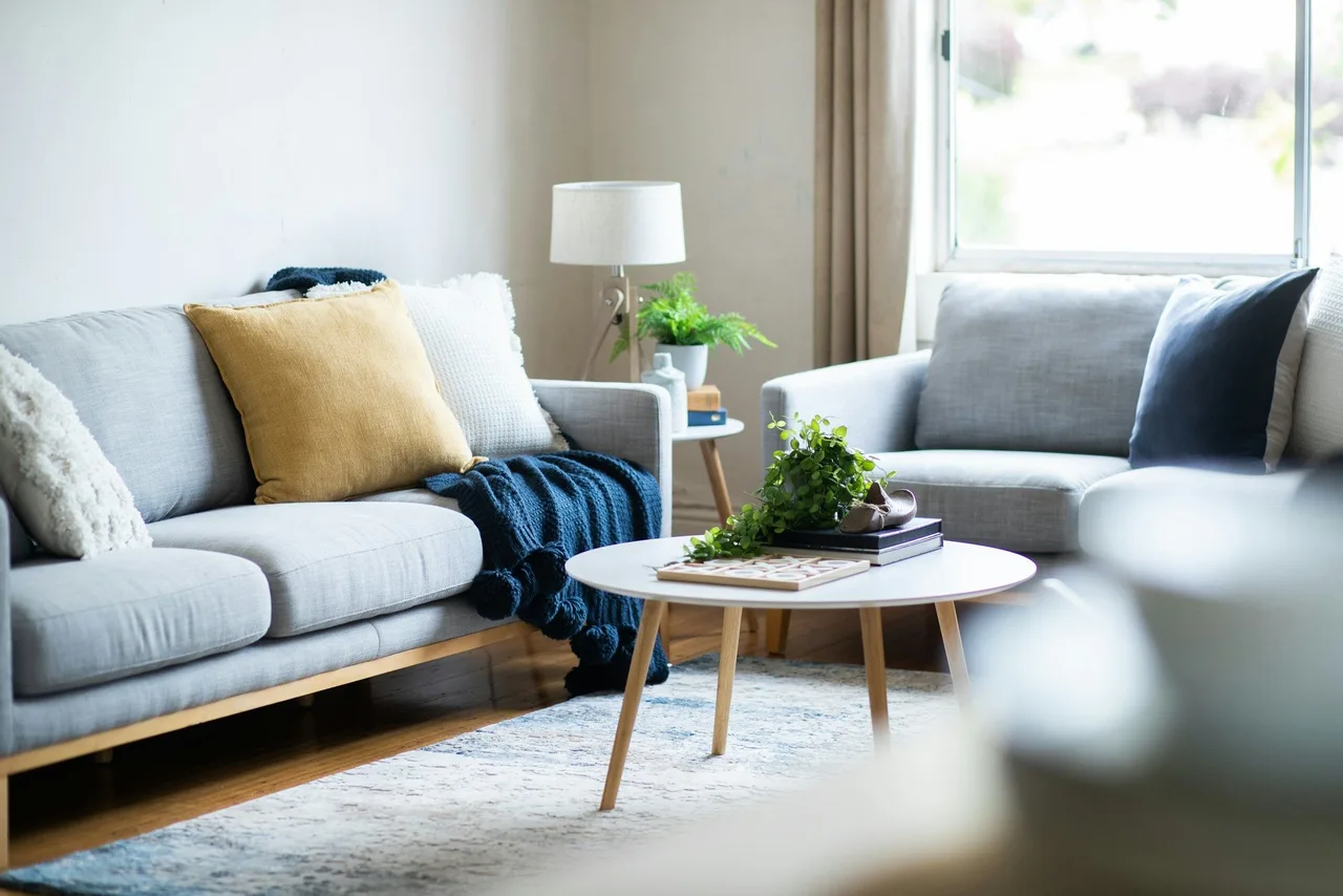 Stock illustration of a light living room with painted walls, timber furniture and soft neutral upholstery.