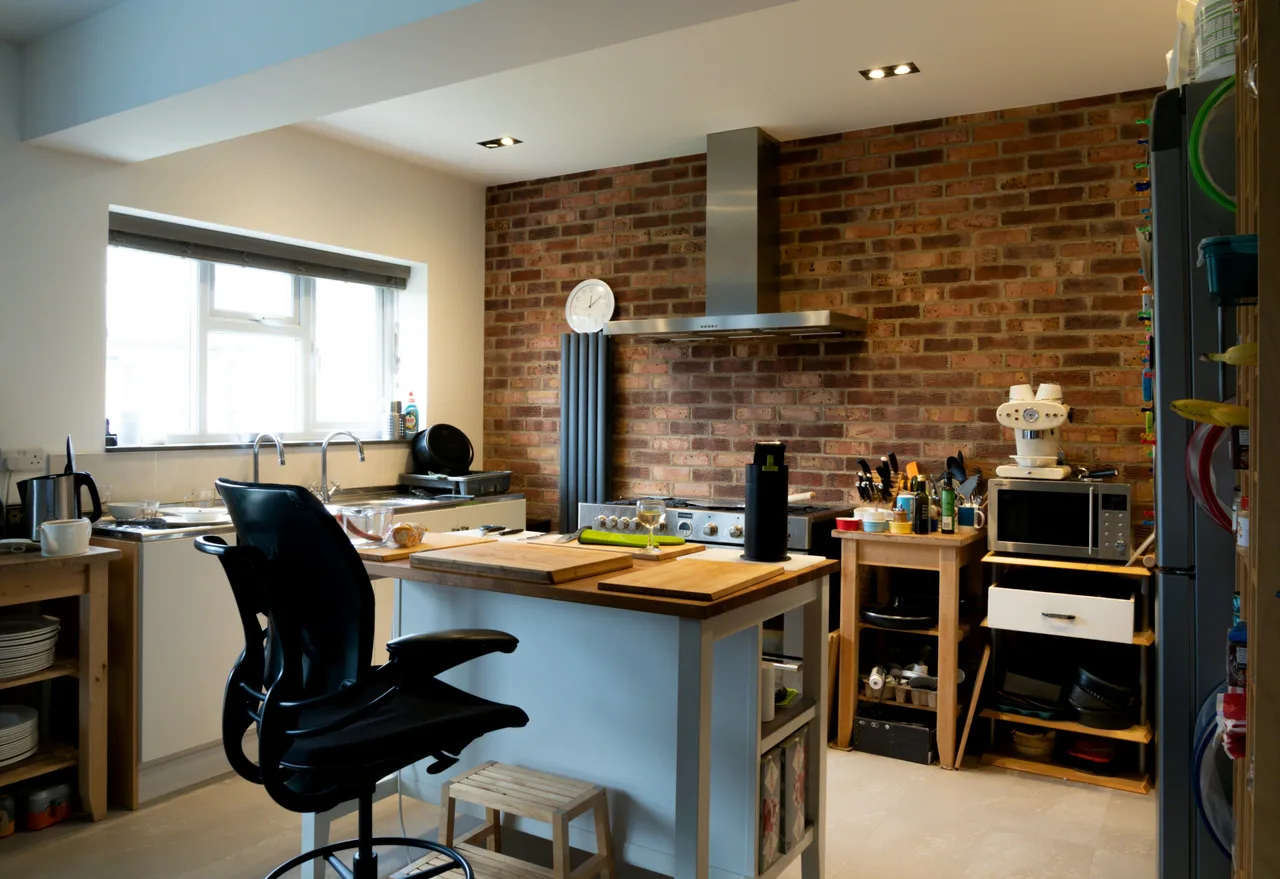 Stock illustration of a lived-in kitchen with an exposed brick wall, timber worktop and daylight.