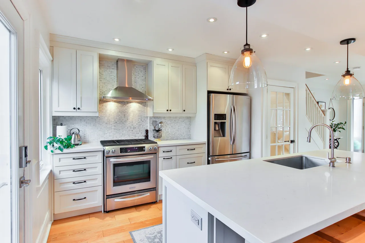 Stock illustration of a light kitchen with shaker cabinetry, an island and pendant lighting.